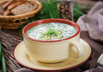 Summer yogurt cold soup with egg, cucumber, and dill on wooden table. Okroshka. Russian food
