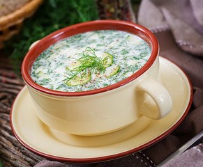 Summer yogurt cold soup with egg, cucumber, and dill on wooden table. Okroshka. Russian food