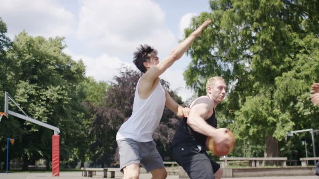 Basketball player scores against the offence in an outdoors game, in slow motion