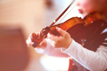 Child playing the violin in a room
 - obrazy, fototapety, plakaty