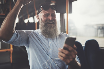 Mature man listening to music and laughing on a bus