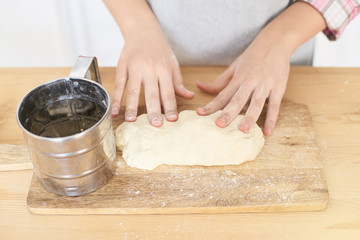 Preparation of the test. Small hands. Wooden table. White flour