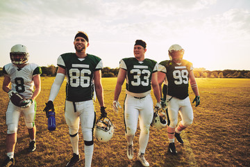 Smiling team of American football players walking off a field