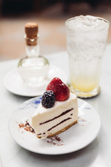 Slice of strawberry cheesecake topping with fresh strawberry and blackberry. Served with soda mocktail and syrup.