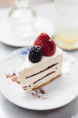 Slice of strawberry cheesecake topping with fresh strawberry and blackberry. Served with soda mocktail and syrup.