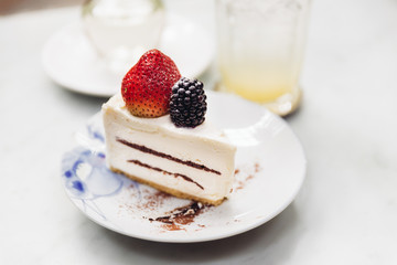 Slice of strawberry cheesecake topping with fresh strawberry and blackberry. Served with soda mocktail and syrup.
