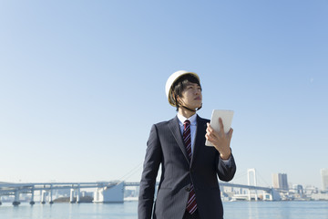 ビジネスマン・ヘルメット・タブレットを持