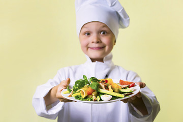 funny boy chef cooked salad with vegetables, cheese and ham on a plate
