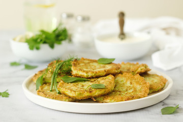 Pancakes from zucchini, served with sour cream or yogurt and various herbs. Useful vegetarian food.