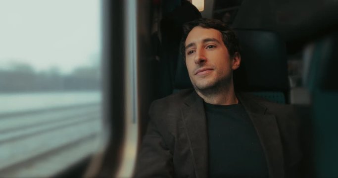 Happy fullfilled man riding train and looking out window