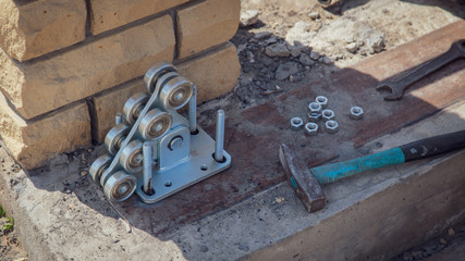 The worker installs rollers on the sliding gate