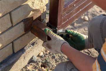 The worker installs rollers on the sliding gate