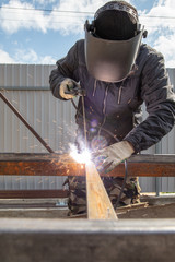 Welder welds metal at the construction site