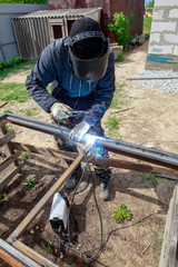 Welder welds metal at the construction site