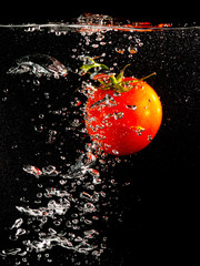 Red tomato in water on a black background
