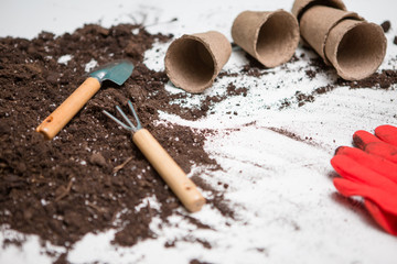 Photo of top soil for transplanting plants, rake, scoop, watering can, red gloves