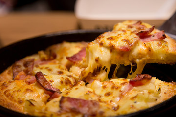 Hot pizza slice with melting cheese on a  table in restaurant pizza Italian food.