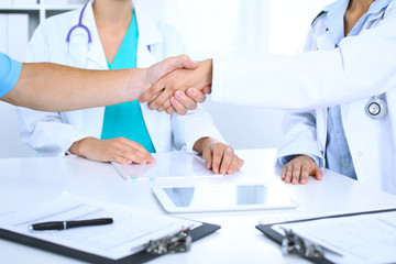 Fototapeta premium Two doctors shaking hands to each other at meeting. Teamwork and agreement in medicine