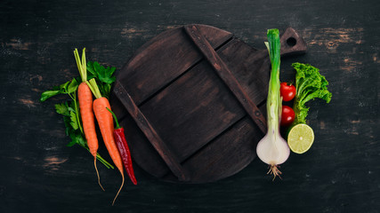 Fresh vegetables and ingredients for cooking around vintage cutting board on rustic background, top view, place for text. Vegan food , vegetarian and healthily cooking concept.