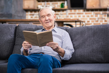 Nice senior man reading a book at home