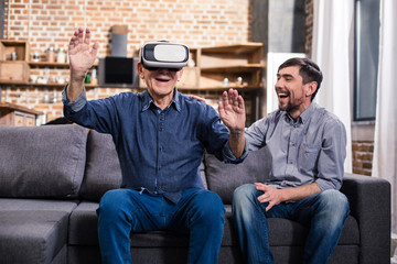 Elderly man using VR device with his son