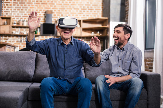 Elderly man using VR device with his son