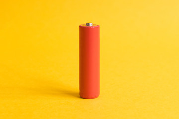 Single red battery on a yellow pastel background