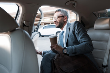 Fototapeta na wymiar businessman with coffee to go sitting in car with opened door