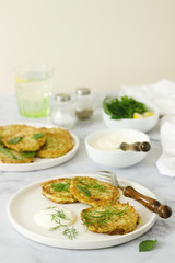 Pancakes from zucchini, served with sour cream or yogurt and various herbs. Useful vegetarian food.