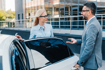 side view of business colleagues having conversation near car on street