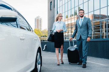 business people with luggage walking to car on parking