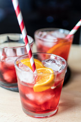 aperitif in the sports bar during a football match: Negroni cocktail with Campari, ice and orange slices, green and black olives