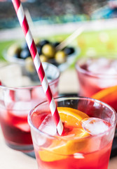 aperitif in the sports bar during a football match: Negroni cocktail with Campari, ice and orange slices, green and black olives