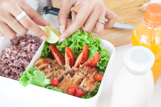 Woman's hands preparing healthy food in lunch box, Grilled chicken breast with vegetables and steam rice, Healthy breakfast
