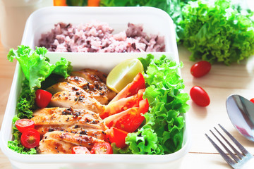 Grilled chicken breast with tomatoes, lettuce and steam rice in lunch box. Close up, Healthy food