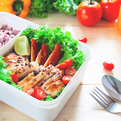Healthy lunch box with grilled chicken, lime, tomatoes, lettuce and rice berry.