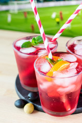 aperitif in the sports bar during a football match: Negroni cocktail with Campari, ice and orange slices, green and black olives