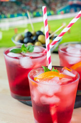 aperitif in the sports bar during a football match: Negroni cocktail with Campari, ice and orange slices, green and black olives