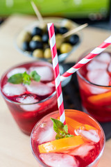 aperitif in the sports bar during a football match: Negroni cocktail with Campari, ice and orange slices, green and black olives