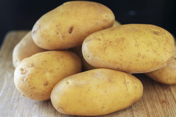 Raw young potatoes in a peel on a black background