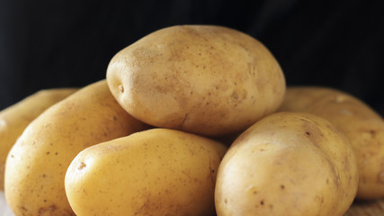 Raw young potatoes in a peel on a black background