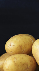 Raw young potatoes in a peel on a black background