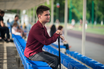 Young lame man sitting in the stadium
