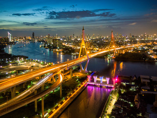 Fototapeta premium Aerial view of Bhumibol suspension bridge cross over Chao Phraya River in Bangkok city with car on the bridge at sunset sky and clouds in Bangkok Thailand.