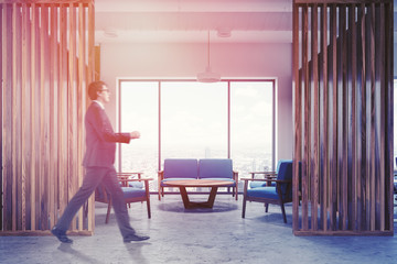 Wood office waiting room interior, blue sofas man
