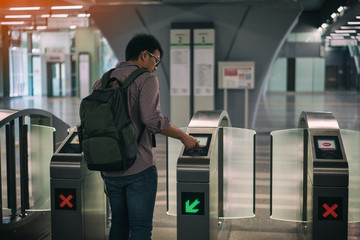 Young asian traveler using smart card pass the door at Mass Rapid Transit (MRT) train in Kuala...