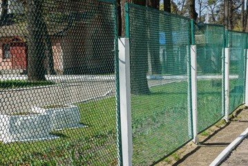 part of an iron fence made of green mesh on the street