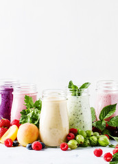 Healthy and useful colorful berry smoothies with yogurt, fresh fruit and berries on a gray background, selective focus
