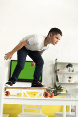 Obraz premium pre-adolescent boy standing on skateboard on table at home