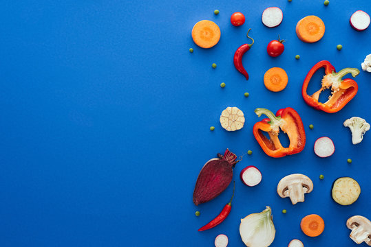 top view of raw sliced vegetables on blue background